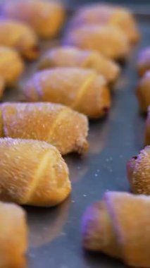 Tepside şeker serpiştirilmiş taze pişmiş tatlı kruvasanlar var. Modern pastanede lezzetli hamur işleri. Kapatın. Dikey video