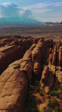 Utah, ABD 'deki Arches Ulusal Parkı' nın kayalık tepeleri. Güzel güneşli bir manzara. Arka planda dağın tepesinde bulutlu bir manzara var. Dikey video