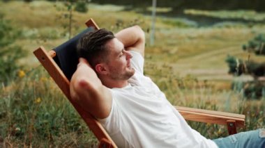 Kafkasyalı bir adam doğada dinleniyor. Adam rahat bir şekilde katlanır sandalyeye oturur ve etrafa bakar..