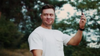 Gülümseyen sakallı adam telefonunda görüntülü konuşma yapıyor. Şehirden uzakta sohbet eden bir adam..