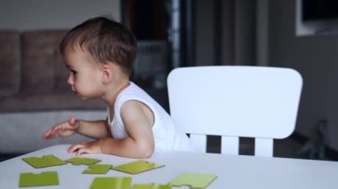 Tatlı küçük oğlan bulmaca oynamaktan yoruldu. Çocuk masadan kalktı ve heyecanla atladı..