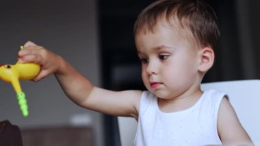 Kafkasyalı tatlı çocuk oyuna odaklanmış. Tatlı çocuk oyuncak bir kuşla oynuyor. Kapat..