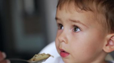 Yemek yemeyi reddeden yaramaz bir çocuğun yüzü. Israrcı anne oğluna yemek vermeyi başarıyor. Portreyi kapat.
