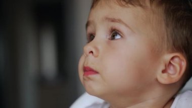 Ağzında yemek olan sevimli bebek yüzlü. Çocuk yemek yemeyi reddediyor, başını çeviriyor. Çok yakın çekim..