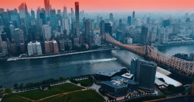 Doğu Nehri üzerindeki Queensboro Köprüsü 'nün altından geçmek için nehir kıyısına giden yat. Gün batımında pembe gökyüzünün altındaki New York gökdelenlerinin muhteşem manzarası. Hava perspektifi.