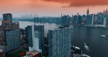 New York 'un üzerinde pembe bulutlu bir gökyüzü. Rıhtımdaki gökdelenler boyunca insansız hava aracı görüntüleri yükseliyor..