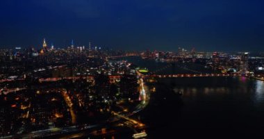 Gece vakti Doğu Nehri 'nin karanlık sularının üzerindeki görüntüler. New York 'un ışıltılı şehir manzarası havadan bakıldığında.
