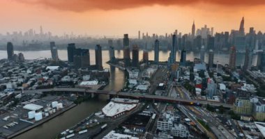 Günbatımında New York 'un görkemli manzarasının üzerinde turuncu gökyüzü. Nakliye gemisi Metropolis 'in yol sisteminden geçiyor. Hava görünümü.