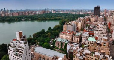 Güzel Central Park 'ı çevreleyen yerleşim yerlerinin üstündeki görüntüler. Parktaki su deposuna yaklaşıyoruz. Arkaplanda New York manzarası.