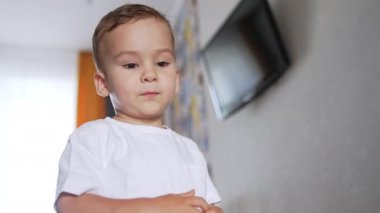 Güzel beyaz çocuk aşağıya odaklanmış görünüyor. Çocuk arkasını döner ve gider. Düşük açı görünümü.