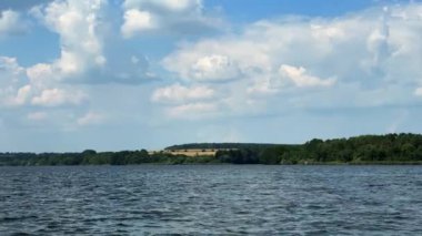 Arkasında nehir ve tarlalar olan güzel bir manzara. Manzaranın üstündeki bulutlu gökyüzü.
