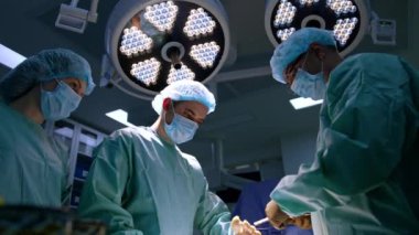 Ortopedi ameliyatının son safhası. Cerrah ameliyat ayağını iplik ve pensle dikiyor. Düşük açı görünümü.