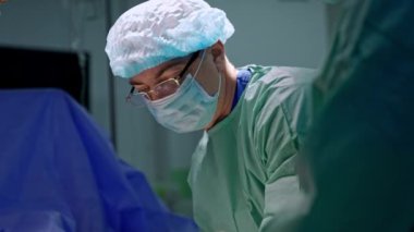Ortopedi cerrahı ameliyat sırasında metal tokmak kullanır. Gözlüklü, şapkalı ve maskeli doktor, portreyi kapat..