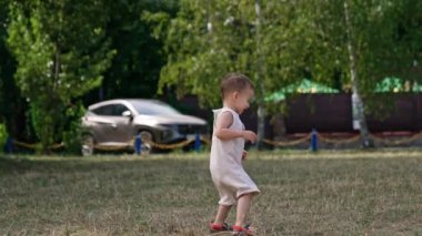 Çimlere basan güler yüzlü bir çocuk. Küçük beyaz çocuk yaz parkında iyi vakit geçiriyor..