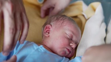 Beşikteki ebeveynlerin elleri bebeğin etrafında. Mavi tulumlu küçük çocuk mışıl mışıl uyuyor. Kapat..