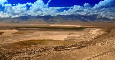 Güneşli sıcak bir günde muhteşem Nevada manzarası. Terk edilmiş topraklar ve beyaz bulutlu açık mavi gökyüzünün altında çıplak dağlar..