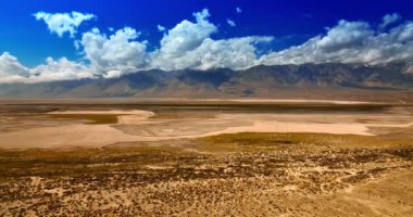 Kaliforniya çölünde çeşitli türde araziler. Muhteşem çıplak kayalar arka planda bulutlarla gölgelenmiştir. Ölüm Vadisi 'nin üst görüntüsü.