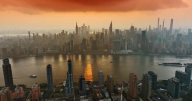 Hudson Nehri 'nin üzerindeki inanılmaz turuncu bulutlar. Günbatımında havadan New York 'un görkemli gökdelenleri.
