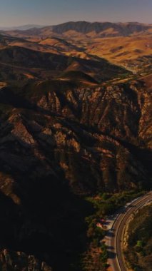 Birleşik Devletler 'deki dağlık arazi. Dalgalı yol kayalık bölgeden geçiyor. Güneşli bir günde yukarıdan Rocky Panorama. Dikey video