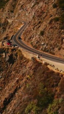 Dağların arasından geçen yol boyunca uçuyor. Kaliforniya, ABD 'deki Big Sur Morro Körfezi' nin büyük kayaları. Dikey video