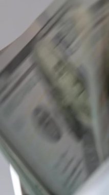 100 dolarlık banknotlar, nakit sayma makinesinin içine düşüyor. Para sayan makine çalışmayı durdurdu. Kapatın. Arkaplan bulanık. Dikey video