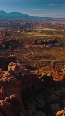 Utah, ABD 'deki Arches Ulusal Parkı' nın yuvarlak kayaları. Mavi gökyüzünün arka planında, dağlık vadinin güneşli manzarası. Üst Manzara. Dikey video