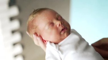 Güzel sarışın bebek annenin elinde uyuyor. Yeni doğmuş bebek annesinin salladığı el sallayarak uyuyordu. Kapat..