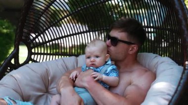 Babası küçük oğlunu kucağına aldı ve onu başından öptü. Baba dışarıda bebeğiyle dinleniyor..