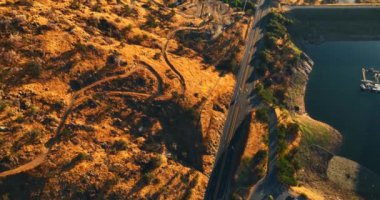 Dağlar ve göl arasında geçen otoyol. California çölündeki kayaların üstündeki drone görüntüleri..