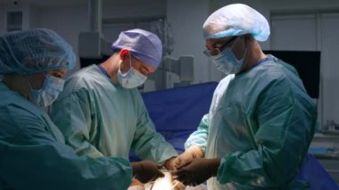 İşlem sırasında metal aletleri kullanan yardımcı cerrahlar. Kadın hemşire doktora bir enstrüman veriyor. Yürüyerek ameliyat..