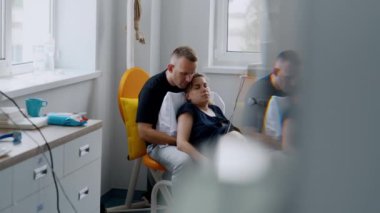 Adam kucağında hamile karısının kollarıyla oturuyor. Kafkasyalı çift hastanede bebek doğurtuyor..