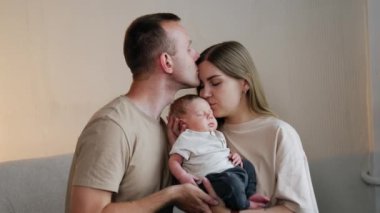 Uzun saçlı kadın uyuyan bebeğini kafasından öper. Aşık bir adam karısını alnından öper..