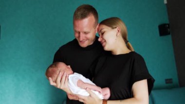 İlk kez ebeveynler yeni doğmuş bir bebeği tutarak bir arada duruyorlar. Çiftler bebeklerine hayranlıkla bakar..