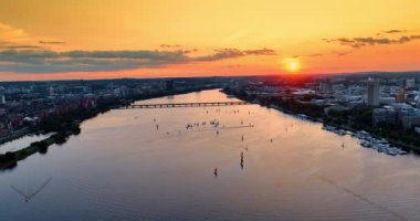 Boston 'daki Charles Nehri üzerinde uçuyor. Şafağın turuncu ışıklarıyla muhteşem şehir manzarası ve su manzarası.