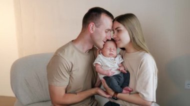 Yeni doğmuş bir çocukla mutlu bir beyaz ailenin portresi. Sevgi dolu ebeveynler, uyuyan bebeklerini iki taraftan ona yaslayarak tutarlar..