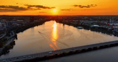 Tek motorlu tekne gün batımında Charles Nehri 'ni geçiyor. Boston, Massachusetts, ABD 'nin turuncu gökyüzünün altından inanılmaz manzarası.