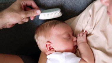 Sevimli yeni doğmuş çocuk annesinin ellerinde rahatça yatıyor. Babamın eli sarışın çocuğun saçlarını tarıyor. Kapat..