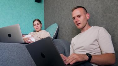 Evde yeni doğmuş bir bebek doğuran genç bir çift. İki ebeveyn dizüstü bilgisayarlarla çalışır ve iş tartışır. Düşük açı görünümü.