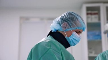 Üniforma giyen beyaz erkek cerrah, şapka maskesi ve röntgenlerden koruyan bir tasma. Ameliyatta asistanlık yapan bir doktorun portresi..