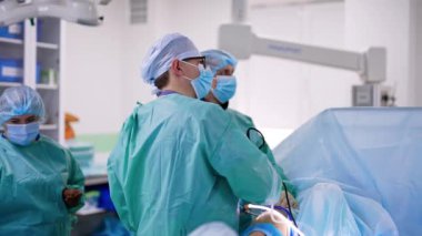 Erkek cerrah laparoskopik ameliyat yapıyor. Profesyonel, modern cerrahi aletler kullanır. Doktorlar prosedürü kontrol eden monitöre bakıyorlar..