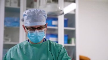 Gözlük takan ciddi bir yetişkin erkek cerrah ameliyatta çalışıyor. Ameliyat yapan bir doktorun portresi.