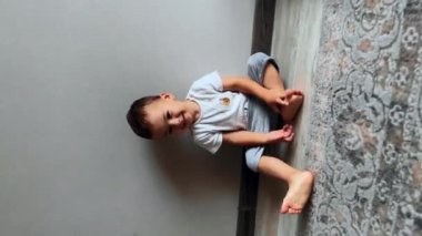 Aktif Kafkasyalı bebek evdeki odada oynuyor. Sevimli çocuk oyuncağı alır ve kameraya gelir. Dikey görünüm.