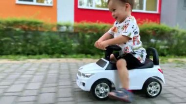 Güzel erkek bebek hızla oyuncak bir arabaya biniyor. Mutlu sağlıklı çocuk yazın dışarıda eğleniyor..