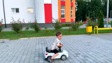 Dışarıda oyuncak bir arabaya binen sevimli gülümseyen çocuk. Mutlu çocuk yazın oyun parkının yakınında vakit geçiriyor..