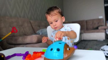 Güzel sakin çocuk evde huzur içinde oynuyor. Bebek masasında oturmuş oyuncaklarıyla meşgul..