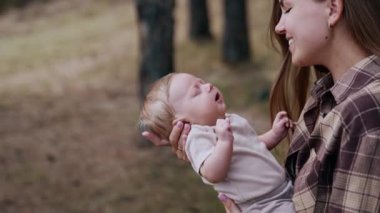 Sevgi dolu anne bebeğini göğsüne yaklaştırıyor. Sonbaharda çocuğu dışarıda olan beyaz bir kadın. Bulanık arkaplan.