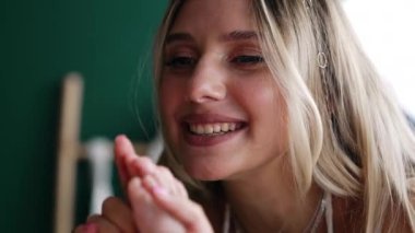 Güzel, gülümseyen sarışın kadın bebeğinin minik ayaklarını tutuyor. Mutlu anne çocuğuyla saklambaç oynayarak oğlunun ayaklarını yüzüne koyar. Kapat..