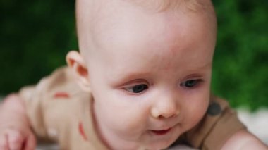 Küçük, tatlı, beyaz bir bebeğin yüzü. Kapatın. Güzel gri gözlü bebek şaşkınlıkla yukarı bakıyor..