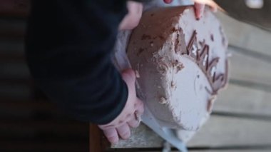 Minik bebek elleri pastaya dokunuyor. Pastadan kremayı lekeleyen bir bebeğin yan görüntüsü. Kapatın. Dikey ekran.