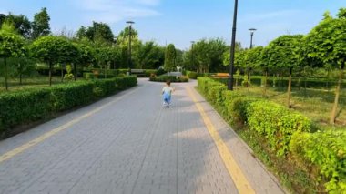 Kot pantolon giyen küçük bebek çocuk yeşil parkta. Aktif çocuk yolda koşar ve durur.
